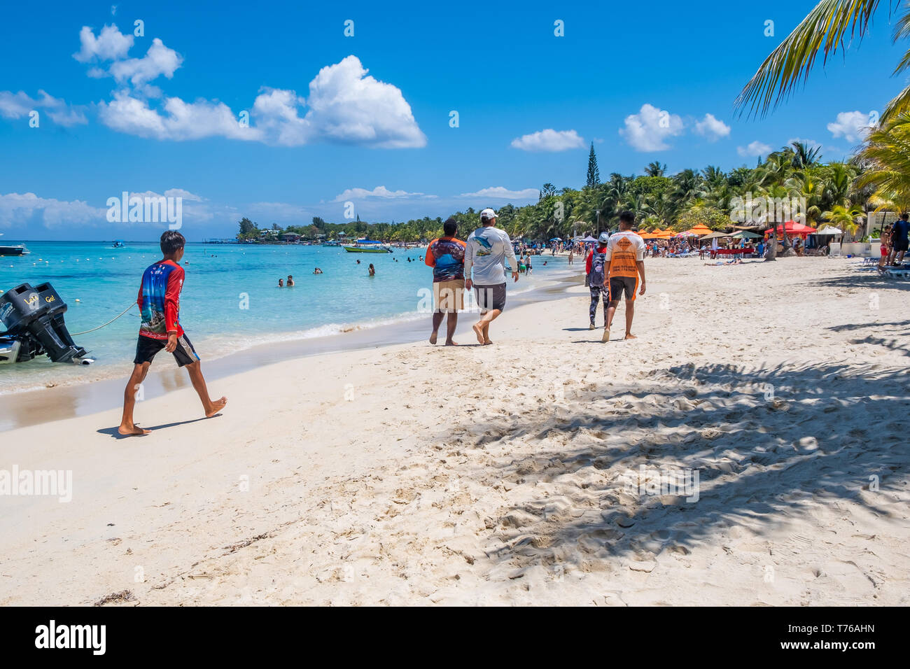 Les touristes et les habitants se promener le long de West Bay Roatan Honduras sur une belle journée ensoleillée. Banque D'Images