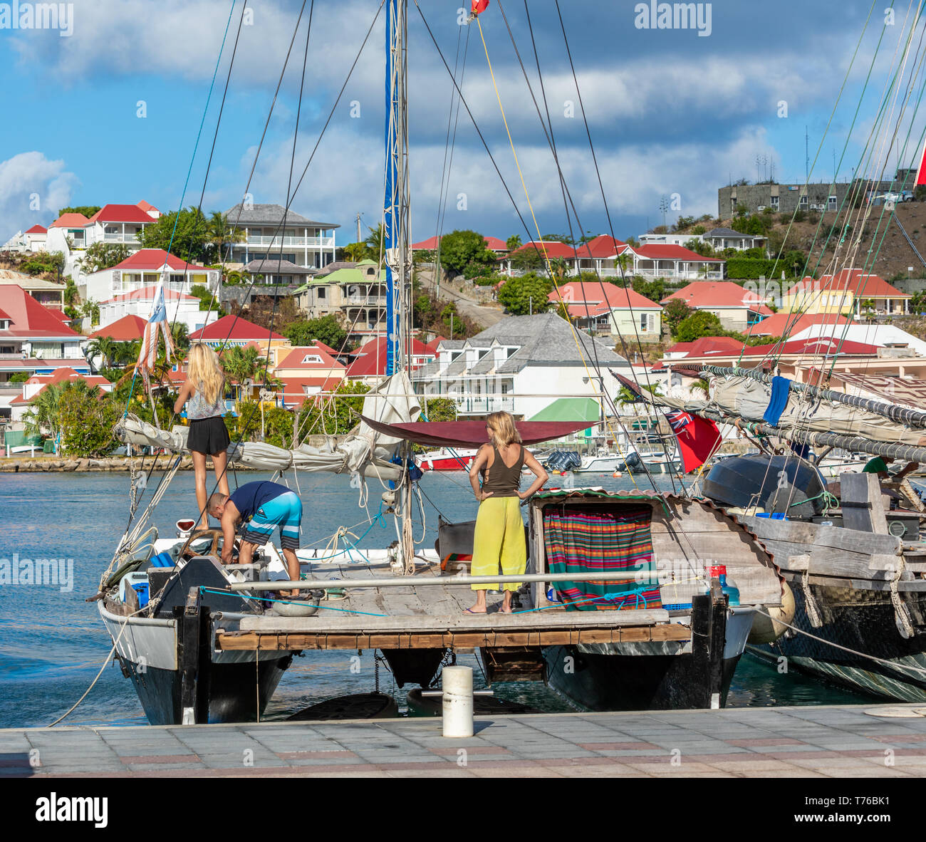 Deux femmes et un homme la mise en place d'un catamaran dans le port de Gustavia, St Barts Banque D'Images