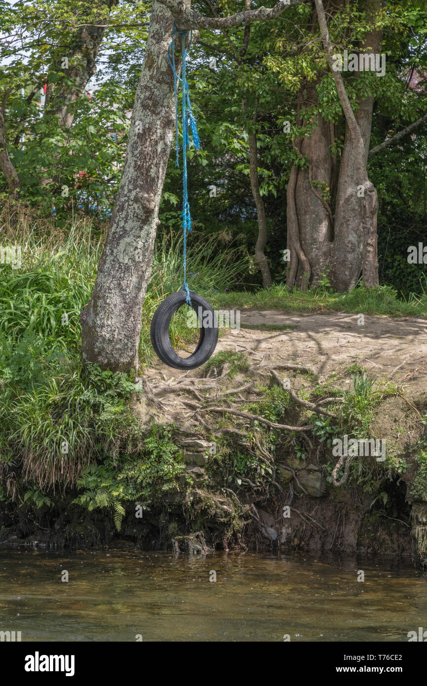Balançoire pneu / tree swing suspendu à une rivière sur l'eau. Les enfants jouer, la métaphore des aventures en plein air, les vacances scolaires. Banque D'Images