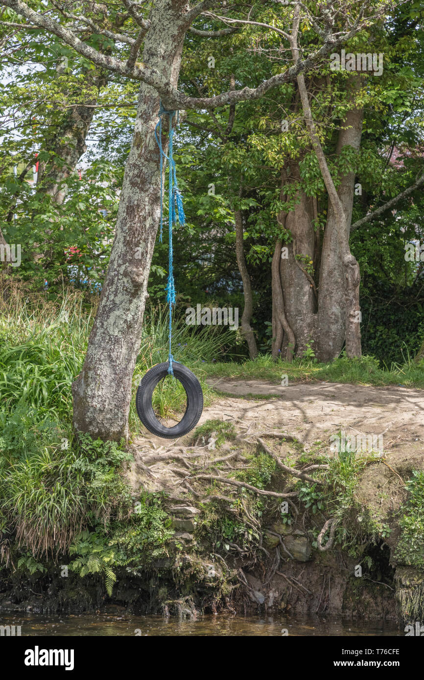 Balançoire pneu / tree swing suspendu à une rivière sur l'eau. Les enfants jouer, la métaphore des aventures en plein air, les vacances scolaires. Banque D'Images