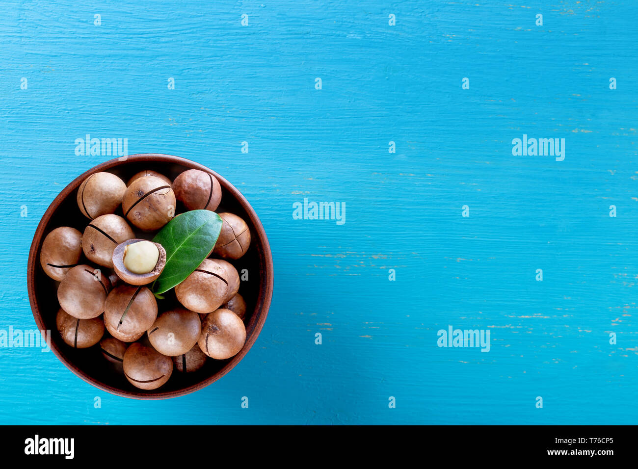 Les noix de macadamia d'Australie avec la feuille de la plaque sur fond de bois bleu Banque D'Images