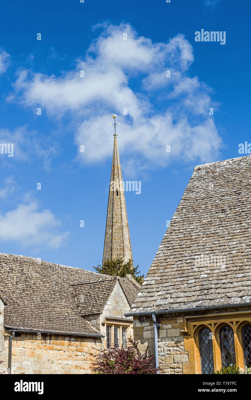 La flèche de l'église de Stanton passant entre deux bâtiments dans les Cotswolds Gloucestershire Angleterre Banque D'Images