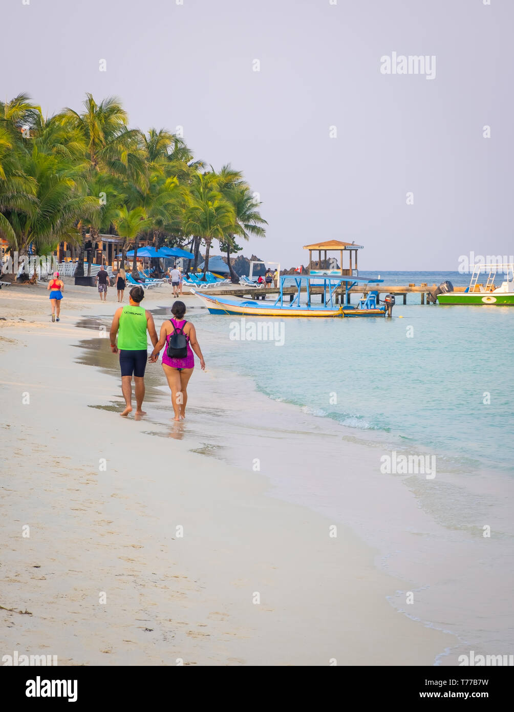 Un homme femme couple marche main dans la main sur la plage de West Bay à Roatan Honduras. Banque D'Images