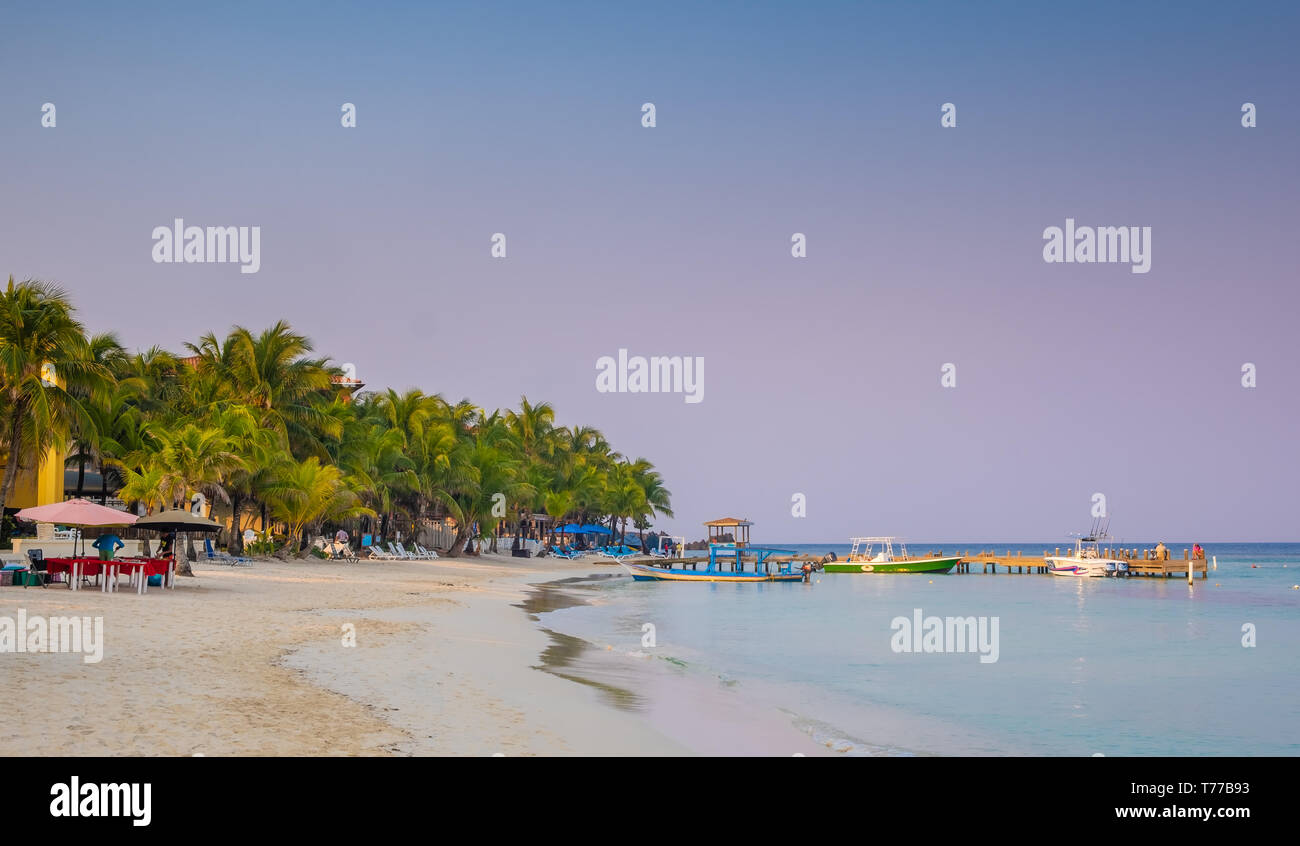 West Bay Roatan Honduras à l'aube avec peu de gens sur la plage. Banque D'Images
