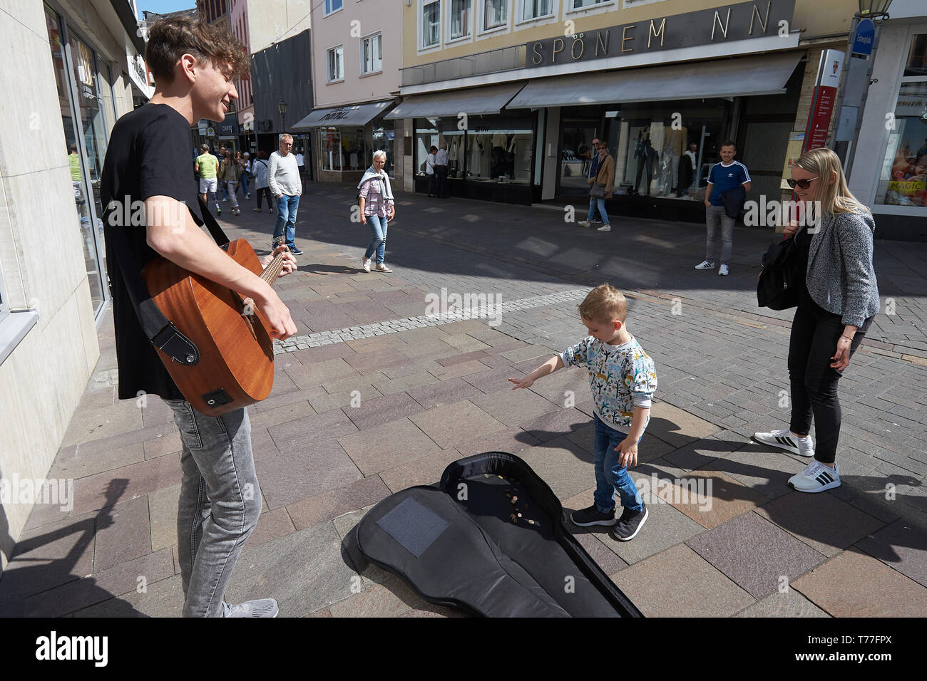 Coblence, Allemagne. 01 mai, 2019. Le chanteur et guitariste Bastian Stein joue dans la zone piétonne, tandis que quatre ans, Julien lance une pièce dans son étui à guitare. Des musiciens de rue peuvent enrichir les centres-villes, mais elles peuvent également provoquer des plaintes. (Dpa-KORR. : 'virtuoses et Nervensägen Straßenmusikern - Wie Städte mit' umgehen vom 05.05.2019). Crédit : Thomas Frey/dpa/Alamy Live News Banque D'Images