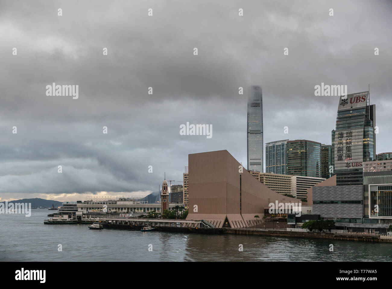 Hong Kong, Chine - 7 mars, 2019 : Très tôt le matin sous la pluie sombre ciel. Toits de Kowloon à Hong Kong Cultural Centre à l'avant. Tour de la CPI à l'arrière. Banque D'Images