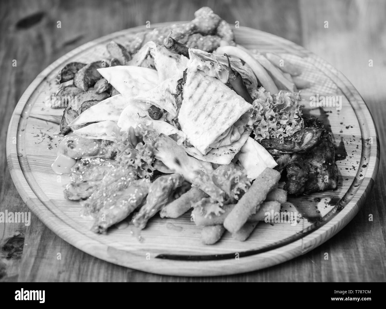 Snack de viande pour le groupe d'amis. De délicieux en-cas savoureux. Les repas au restaurant. Snack pour la bière. Planche de bois frites et bâtonnets de poisson viande burrito steak servi avec une salade. Profitez de votre repas. Menu snack-bar. Banque D'Images