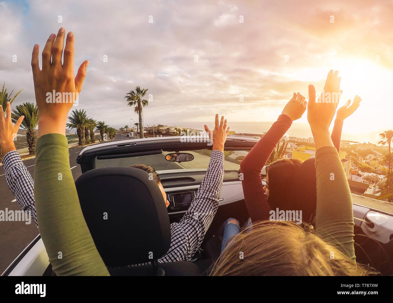 Happy friends having fun in voiture décapotable au coucher du soleil en vacances - Les jeunes de faire partie et de la danse dans une auto cabrio pendant leur voyage en voiture Banque D'Images
