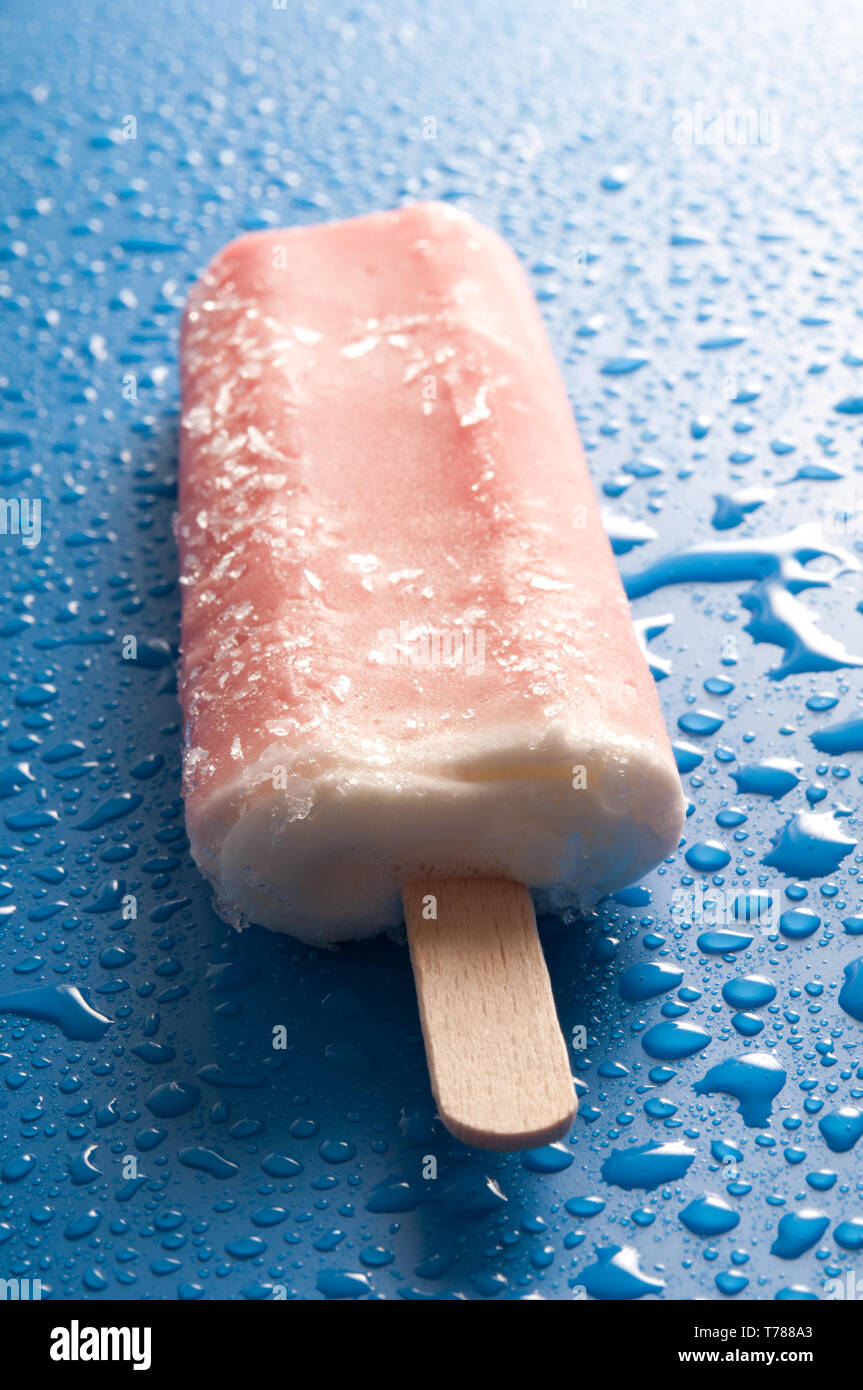 Orange ice lolly pop ou de la glace sur un fond bleu avec des gouttes d'eau Banque D'Images