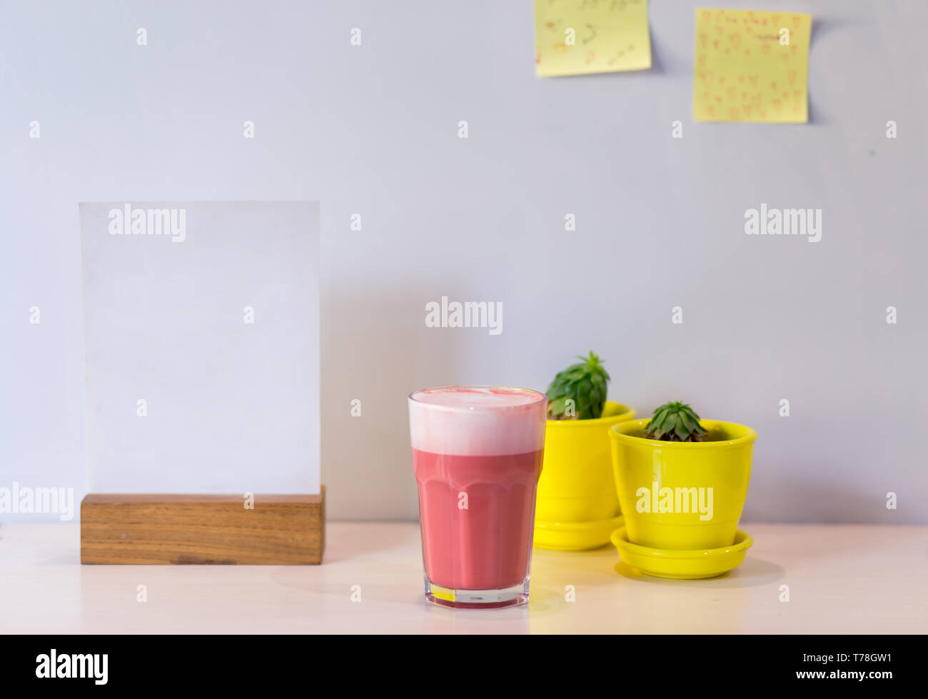 Boisson à la mode, rose latte café avec de la mousse sur la table avec des pots de succulentes jaune dans le café. Copie de l'espace pour menu. Banque D'Images