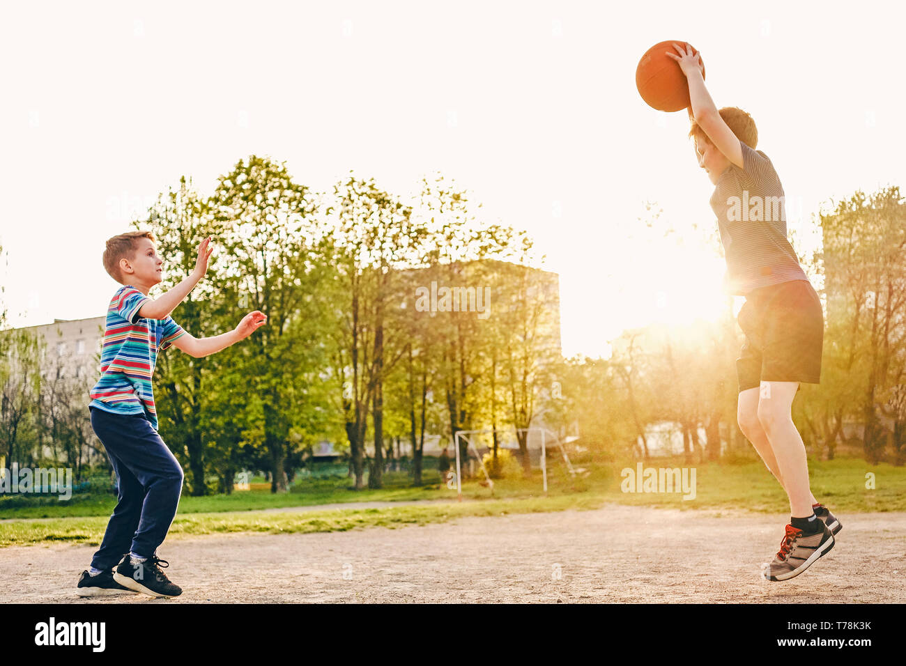 Deux jeunes garçons pratiquent leur compétences en basket-ball chaude soirée de lumière sur un terrain de sport avec un saut pour éviter les mouvements de défense de la deuxième Banque D'Images