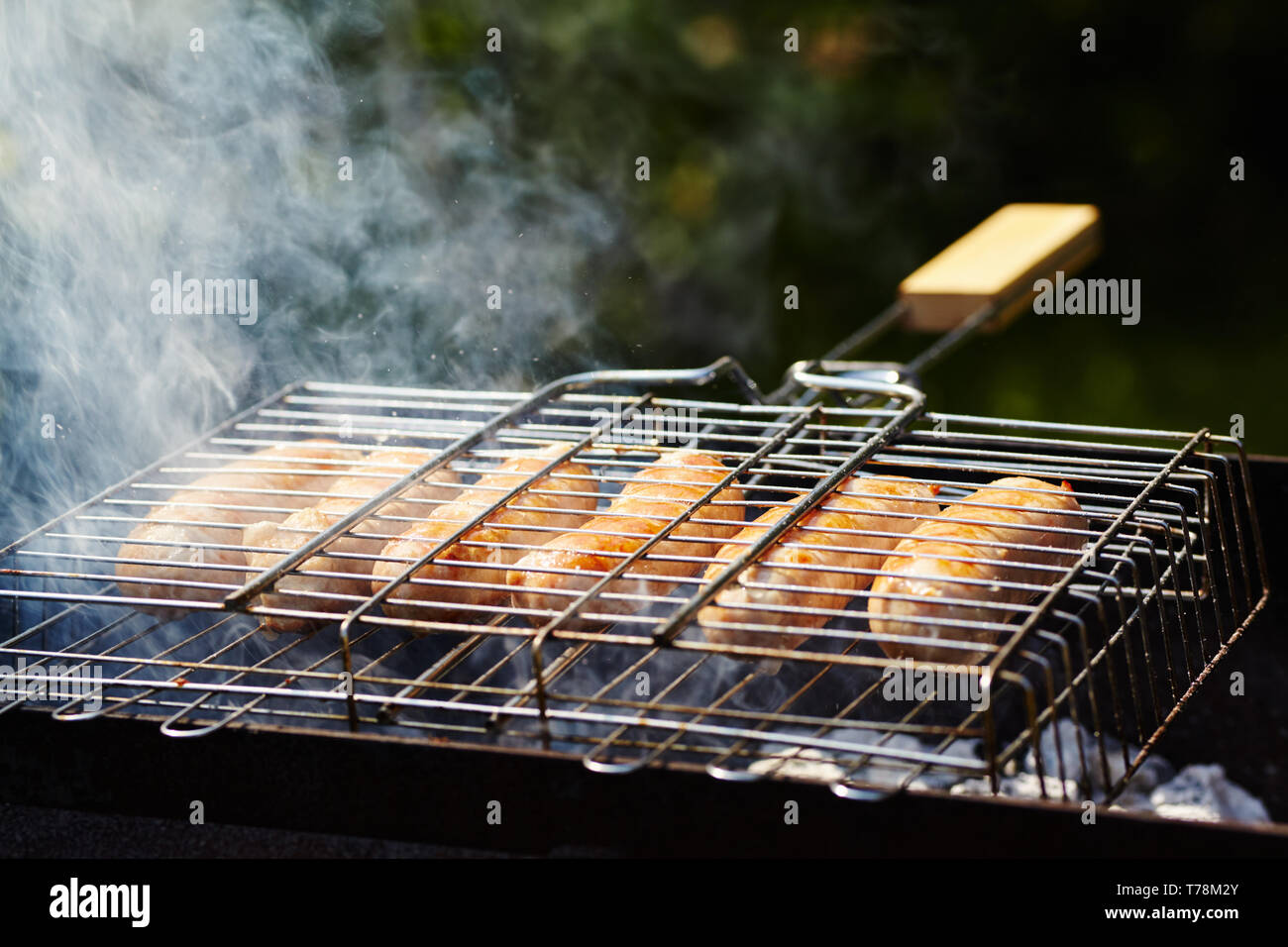 Saucisses rubicund torréfaction sur charbons. Barbecue sur le gril dans la fumée Banque D'Images