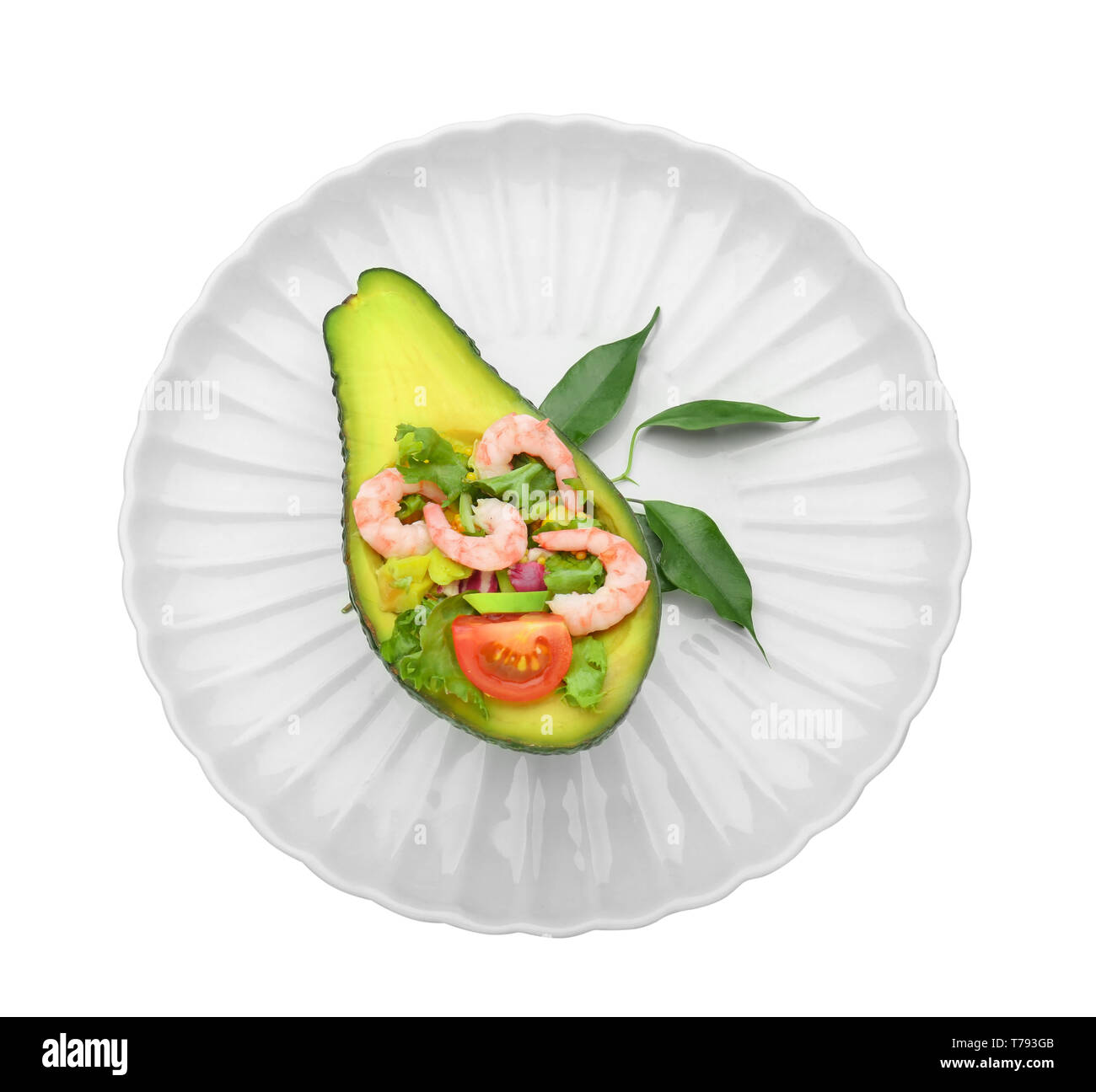 Salade de crevettes savoureuses en bateau sur l'avocat contre la plaque de fond blanc Banque D'Images