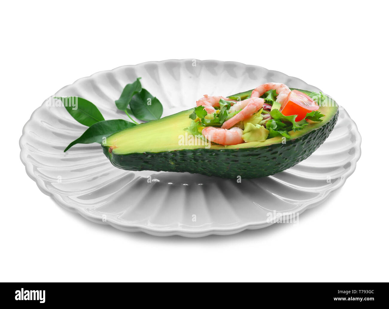 Salade de crevettes savoureuses en bateau sur l'avocat contre la plaque de fond blanc Banque D'Images