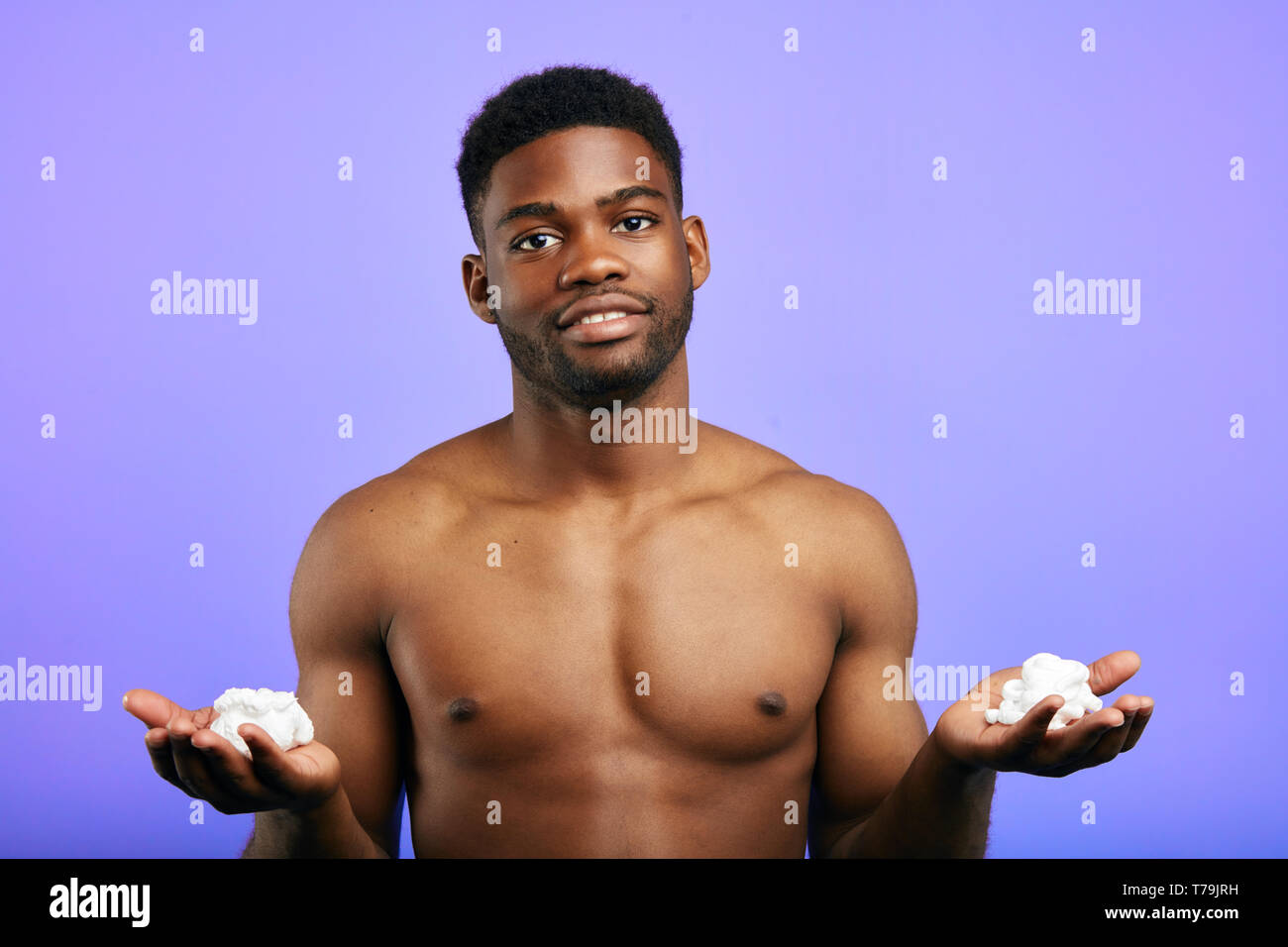 Bel homme splendide tenue de la mousse dans les mains ,la préparation pour le rasage, isolé dans le fond bleu. Banque D'Images