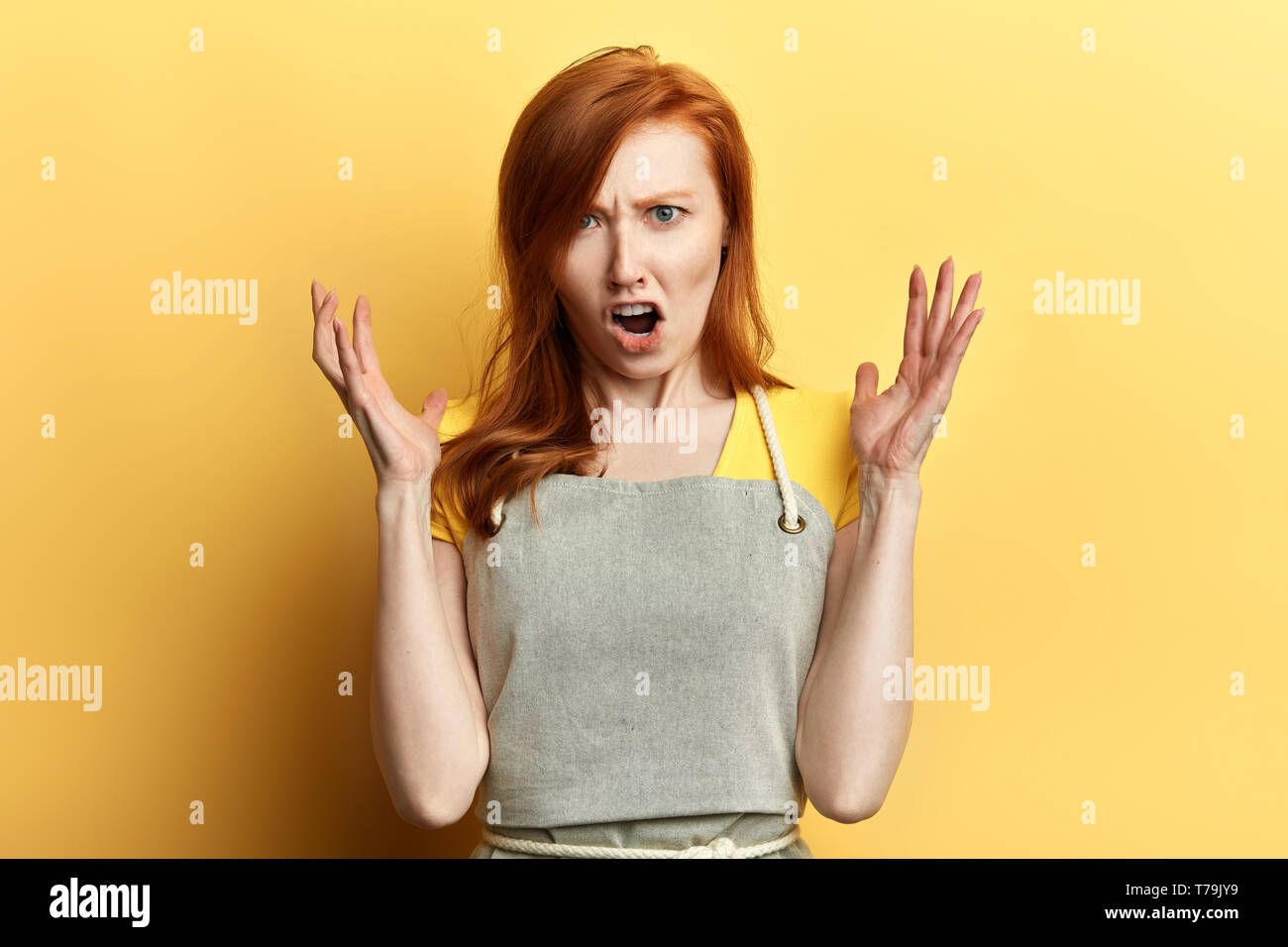 Frustrés girl in apron exprime ses émotions négatives. la photo en gros. sensation, frutration, serveuse de réprimandes, les clients de jeunes femelles garderner shout Banque D'Images