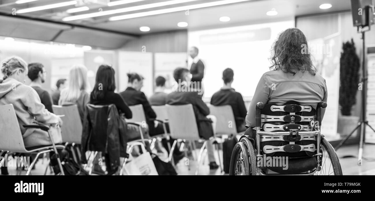 Vue arrière du méconnaissable femme sur un fauteuil roulant qui participent à des discours de conférence. Banque D'Images