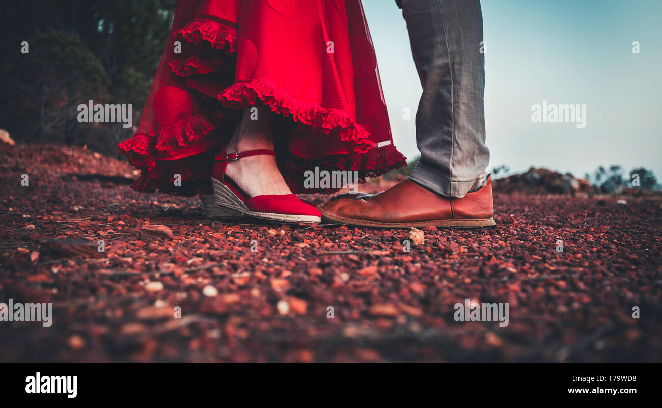 Couple d'âge moyen avec des pieds en gros plan des chaussures en cuir rouge et rouge robe volants en atteignant pour kiss Banque D'Images