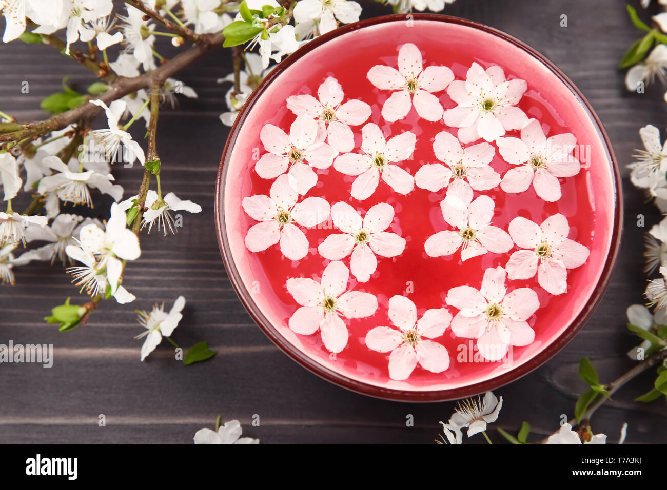 Bol avec de l'eau et de fleurs sur fond de bois Banque D'Images