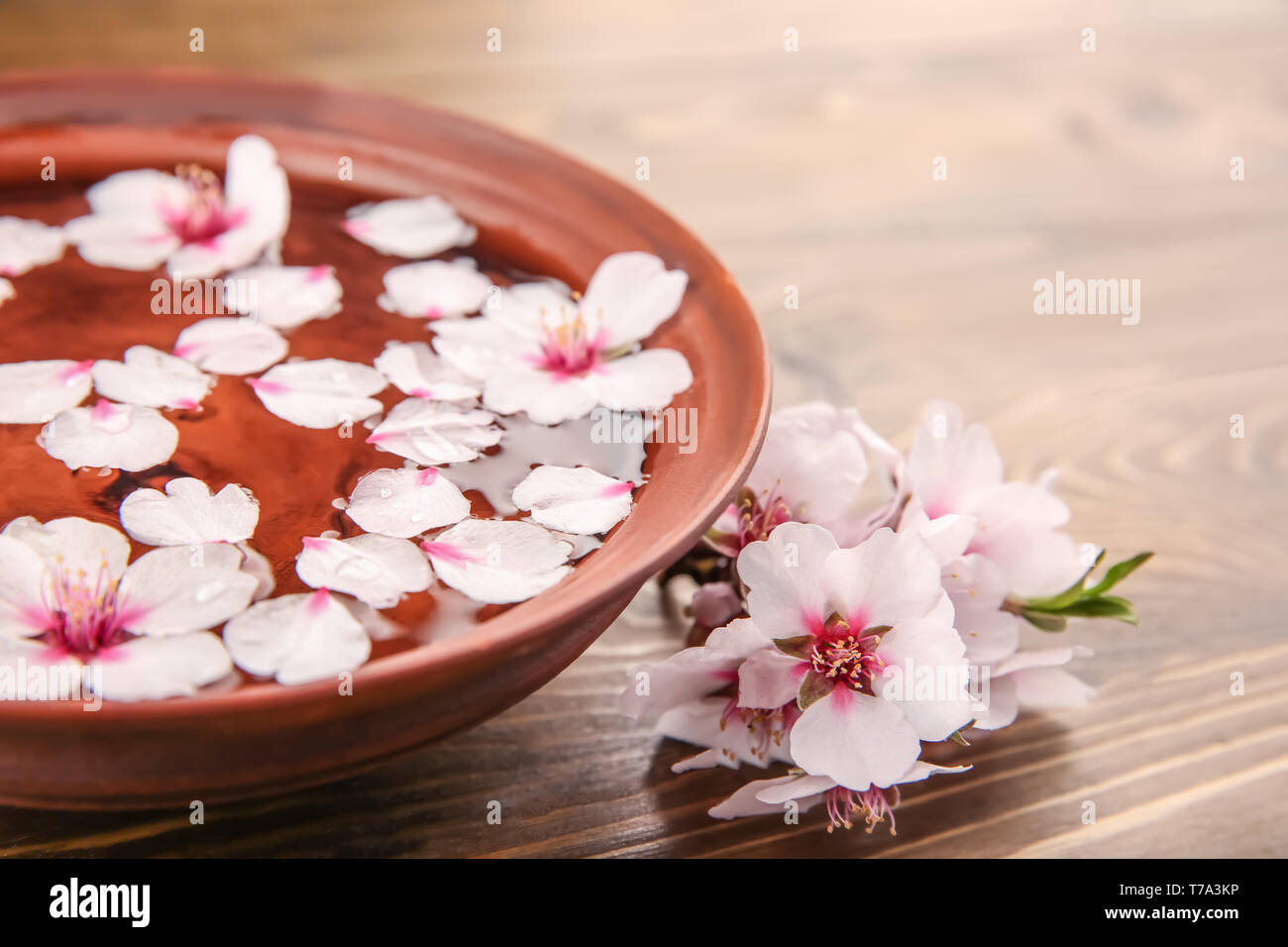 La plaque avec l'eau et fleurs sur fond de bois Banque D'Images