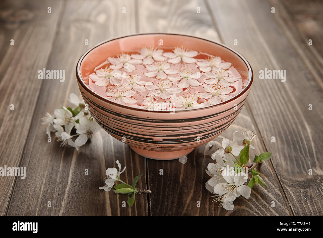 Bol avec de l'eau et de fleurs sur fond de bois Banque D'Images