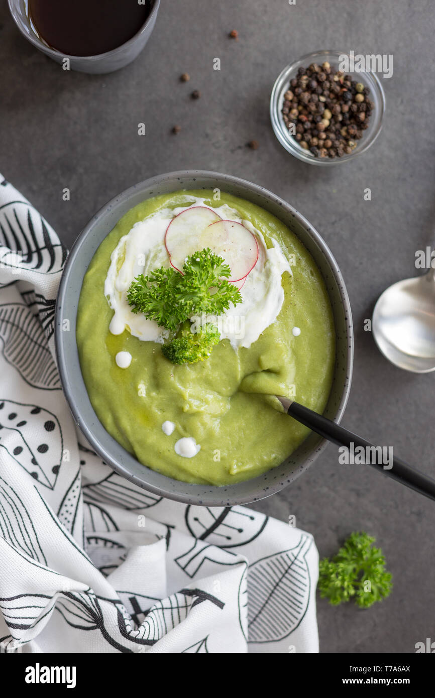 Close up crème délicieuse soupe avec le brocoli et la crème et dans un bol de radis, du pain et une cuillère à fond gris, serviette blanche près de l'arrière-plan sur le béton. Co Banque D'Images Close up crème délicieuse soupe avec le brocoli et la crème et dans un bol de radis, du pain et une cuillère à fond gris, serviette blanche près de l'arrière-plan sur le béton. Co Banque D'Images