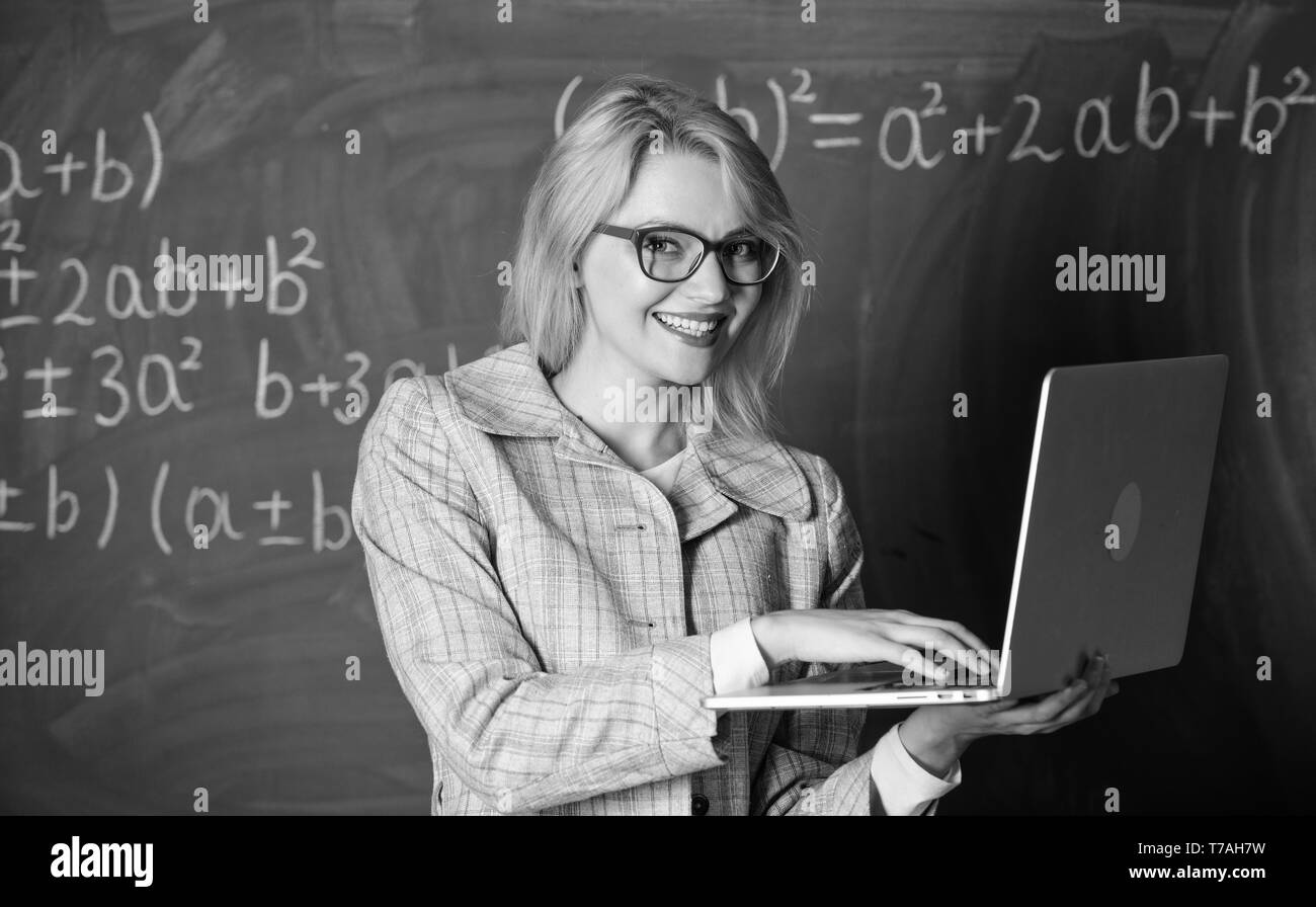 Dame intelligente smart éducateur avec ordinateur portable moderne recherche d'informations d'arrière-plan du tableau. L'apprendre de manière simple. Les technologies numériques concept. Enseignante portent des lunettes est titulaire d'ordinateur portable Internet surf. Banque D'Images