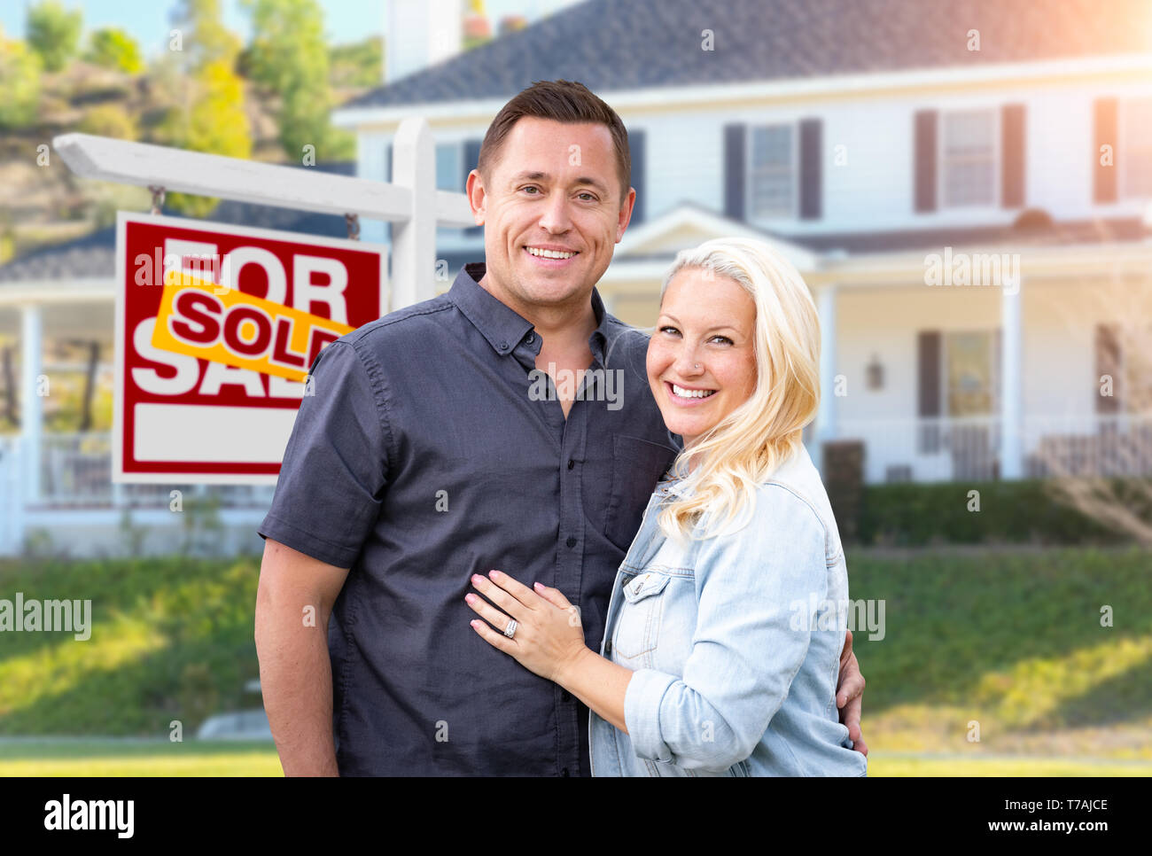 Couple heureux en face de vendu enseigne immobilière et belle maison. Banque D'Images