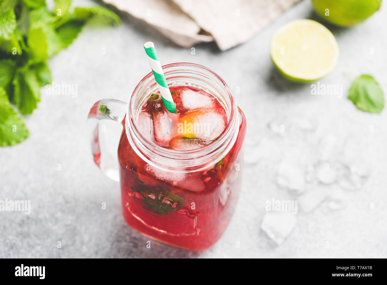 Berry ice tea avec verre tasse avec paille verte sur fond de béton. D'été rafraîchissante boisson froide Banque D'Images