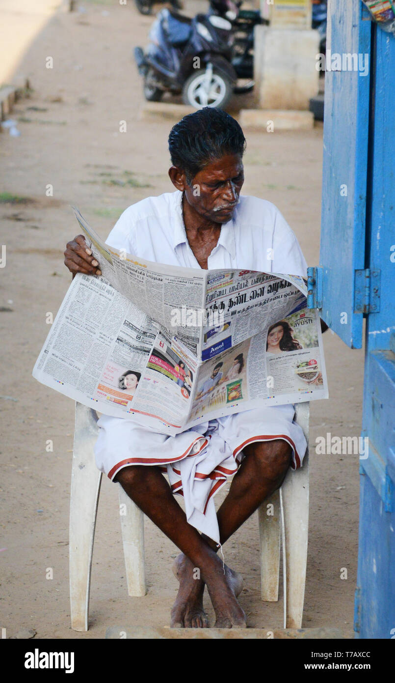 Un Tamoul Man reading the morning news. Banque D'Images