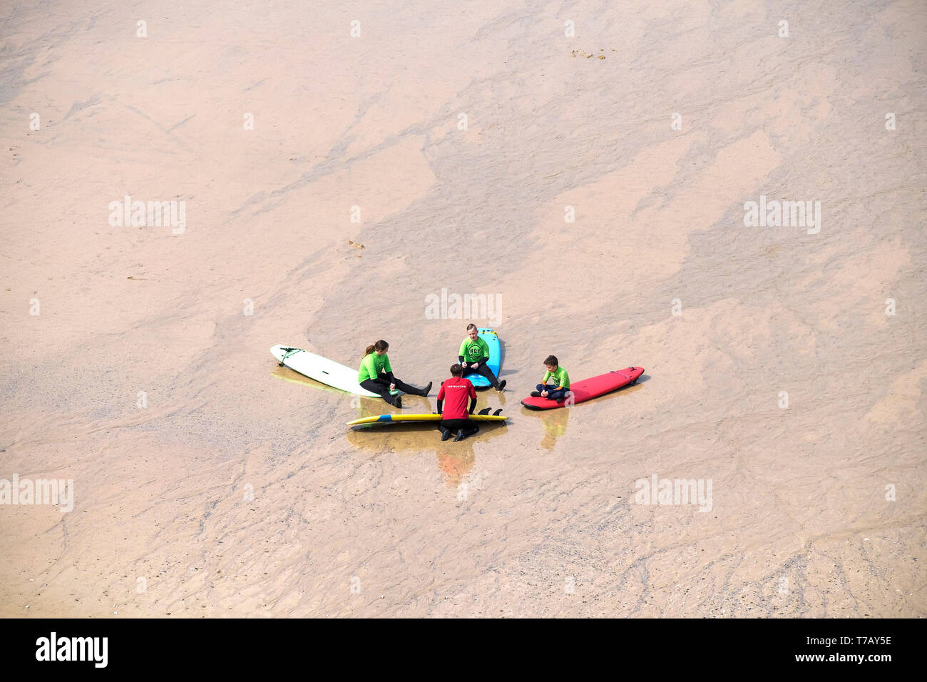 Les jeunes vacanciers, à l'écoute de leur instructeur de surf pendant une leçon de surf sur la grande plage de l'Ouest à Newquay en Cornouailles. Banque D'Images