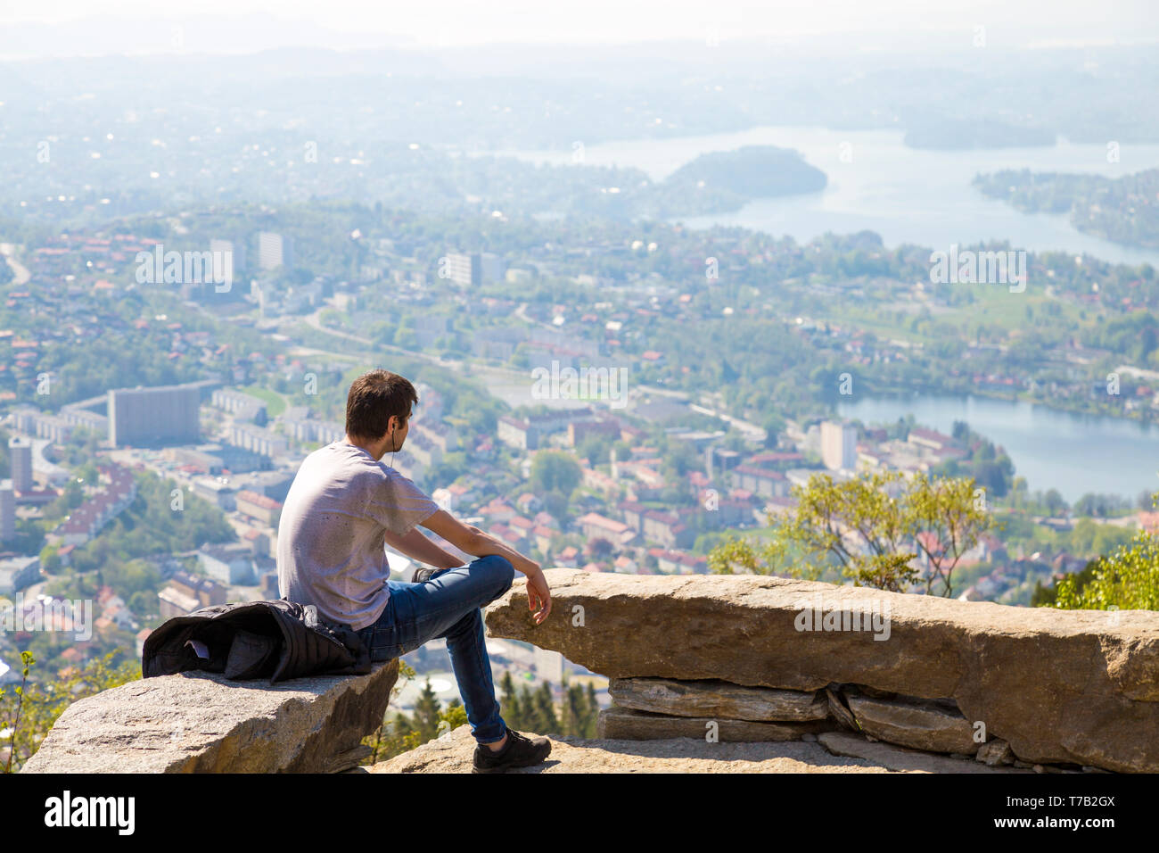 Homme assis seul, écouter de la musique, en regardant une vue panoramique sur Bergen, Norvège du mont Ulriken Banque D'Images