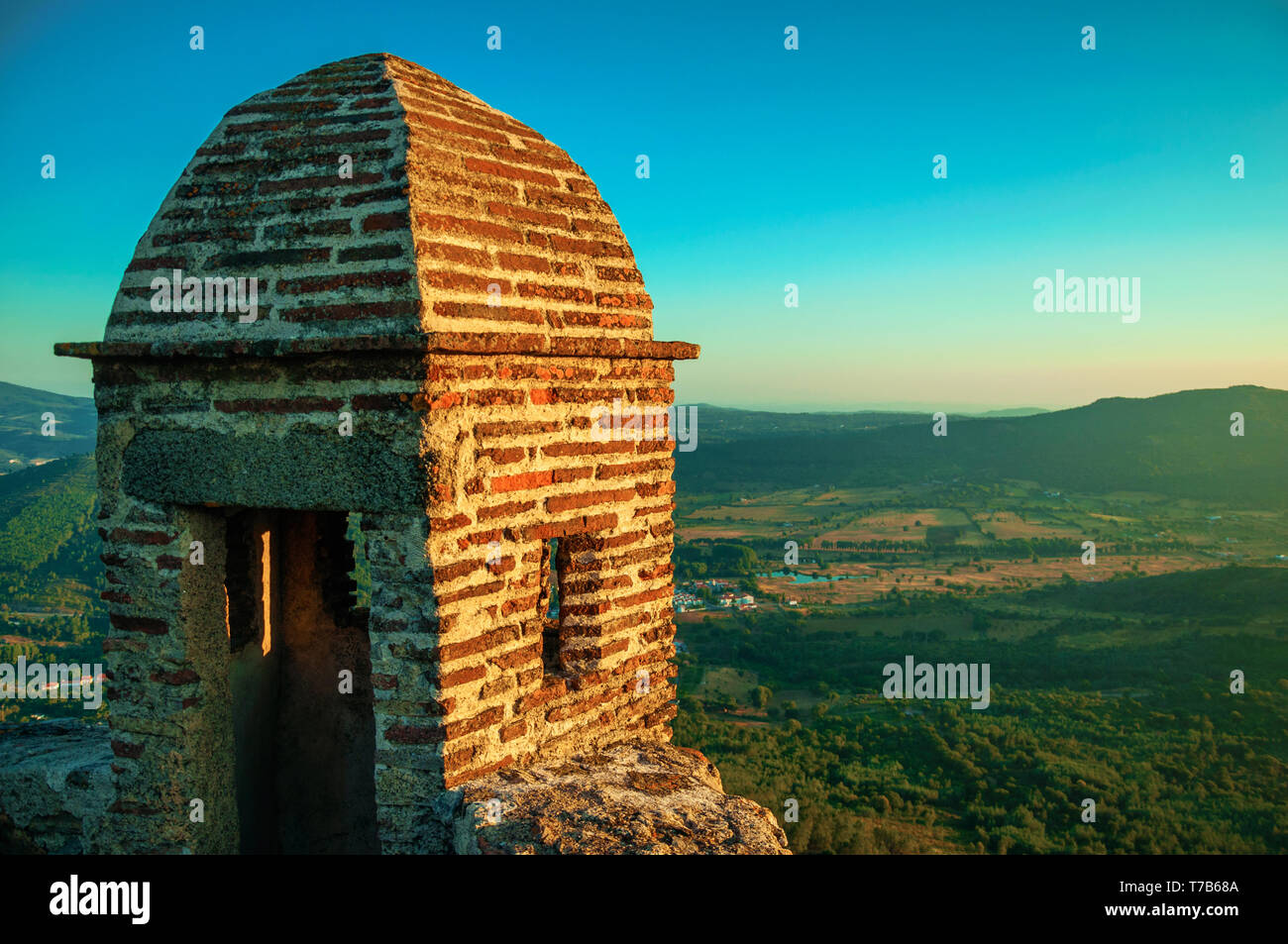 Close-up de la petite tour en briques sur falaise avec paysage vallonné sur le coucher du soleil à Marvao. Un hameau médiéval perché sur un rocher au Portugal. Banque D'Images