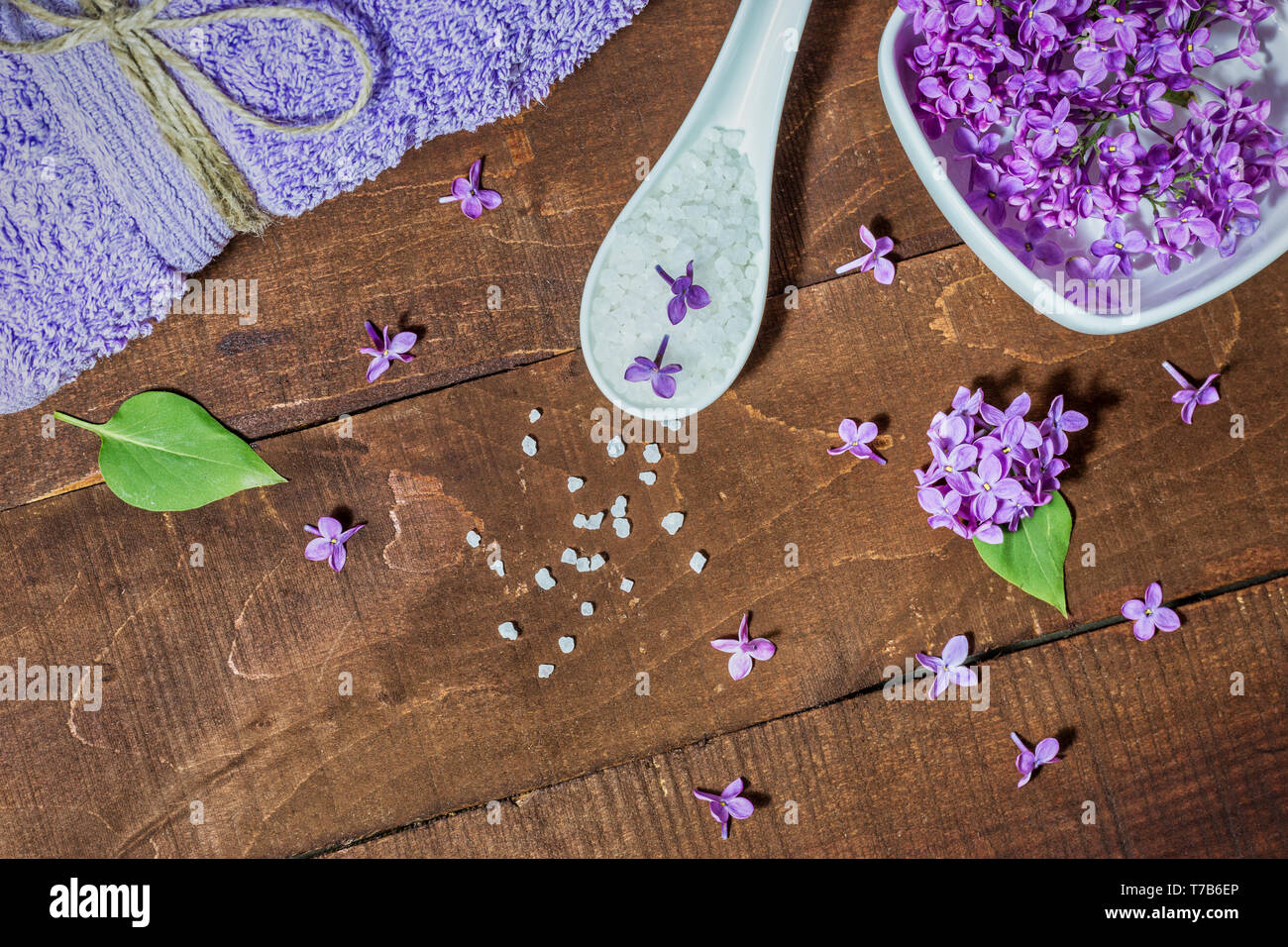 Composition de Spa et de bien-être avec de l'eau fleurs lilas parfumés dans un bol, du sel de mer et de l'absorbant sur fond de bois. L'aromathérapie pour votre détente, vue du dessus Banque D'Images