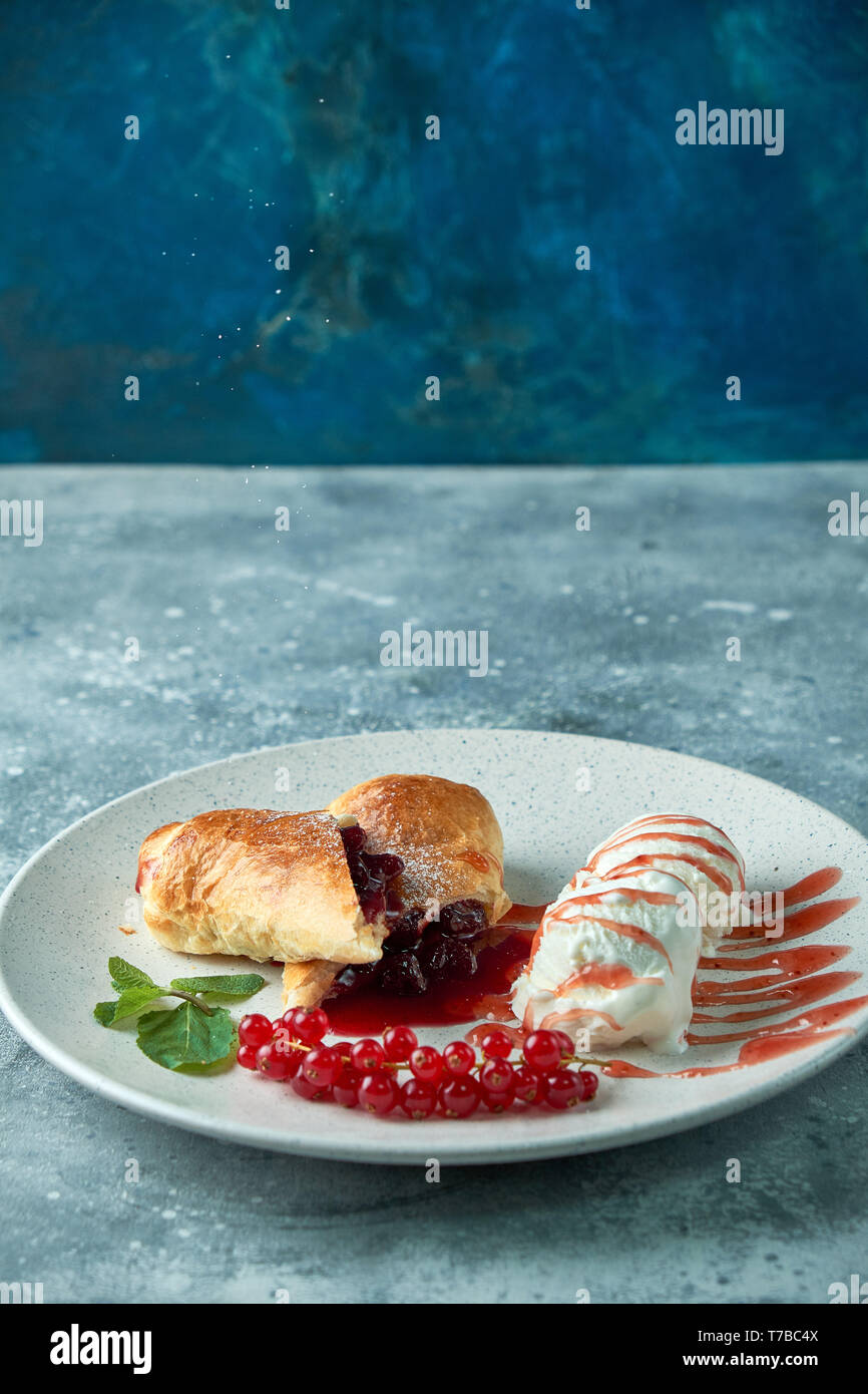 Des tranchées d'un strudel aux fruits rouges frais servi avec des baies de cassis et le sucre en poudre sur une vieille plaque de fond sur un pic avec de la crème glacée Banque D'Images