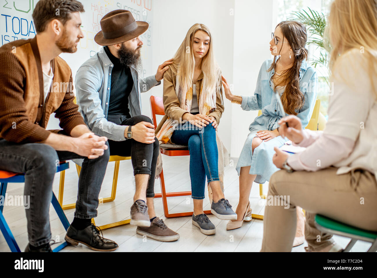 Jeune femme pleurer pendant la thérapie psychologique avec groupe de personnes soutenant sa dans le bureau Banque D'Images