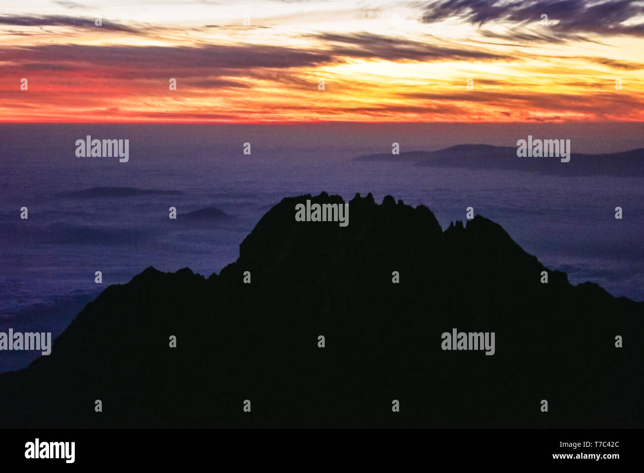 L'Orange soleil se lève sur l'horizon, la lumière qui tombe sur les nuages près des sommets des montagnes. Les pierres noires. Aventures et voyage en Afrique. Banque D'Images