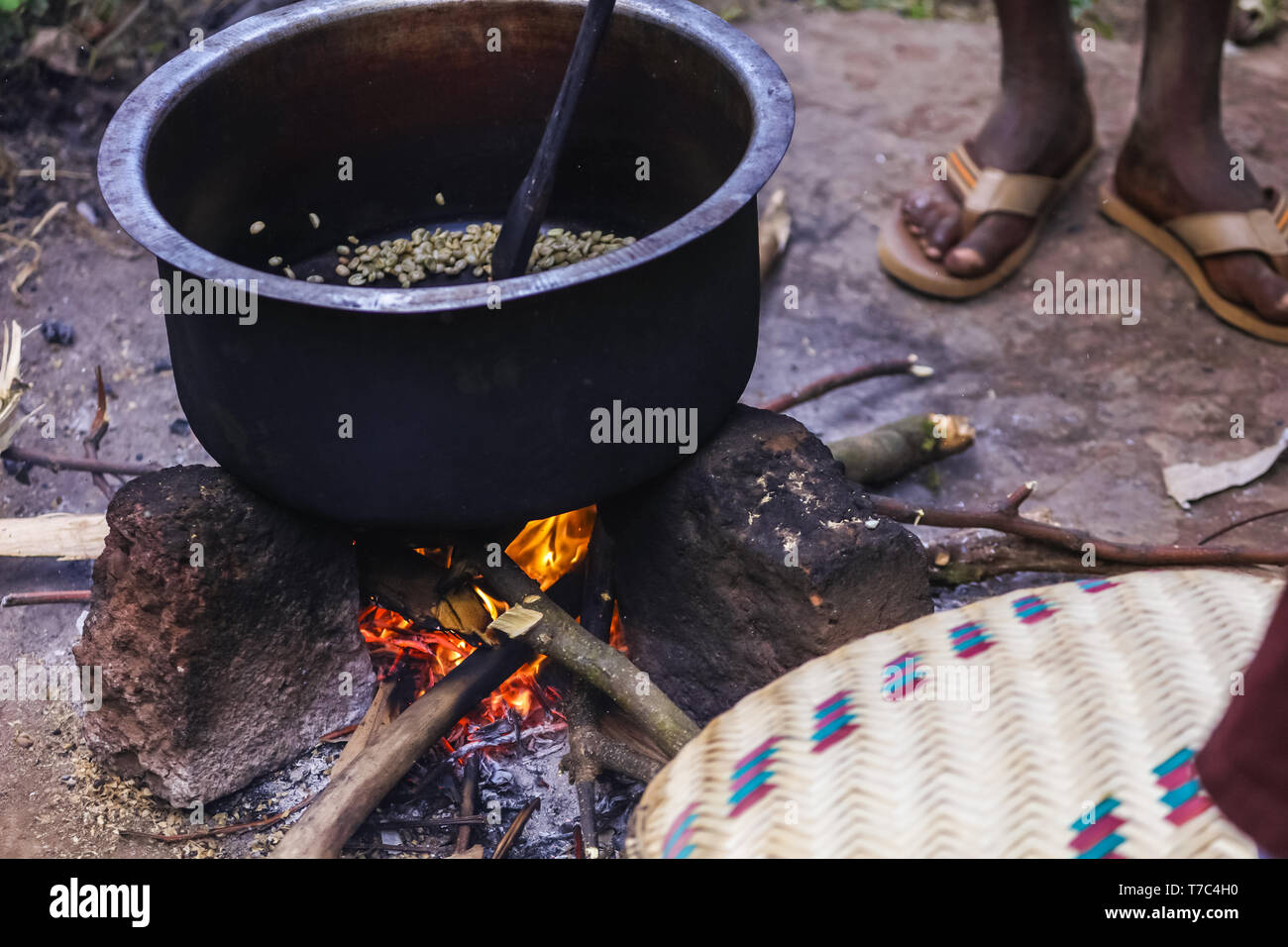 L'Afrique traditionnelle matin près du feu avec des aromatiques tasse de café torréfié. Grand pot profond avec des grains de café vert sur le feu ouvert. Banque D'Images