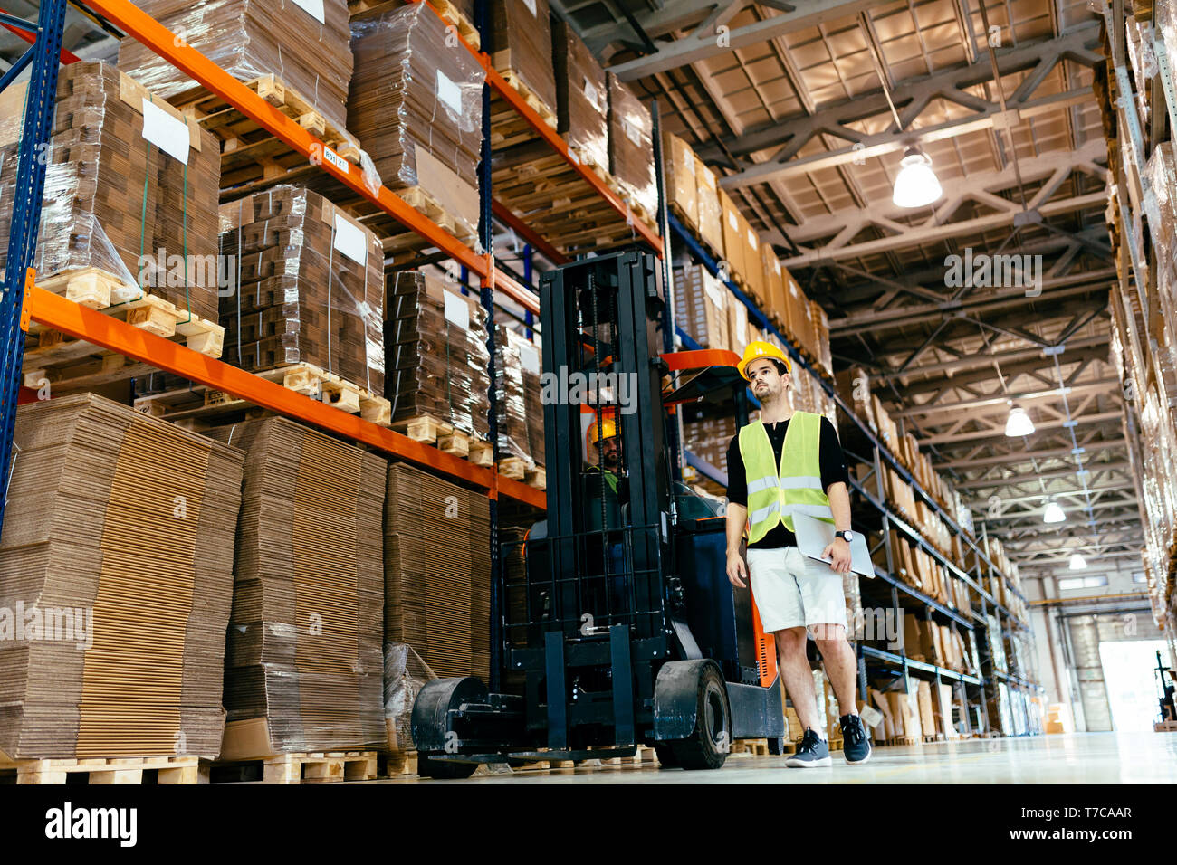 Employé de l'entrepôt logistique faisant travailler avec chargeur chariot élévateur Banque D'Images