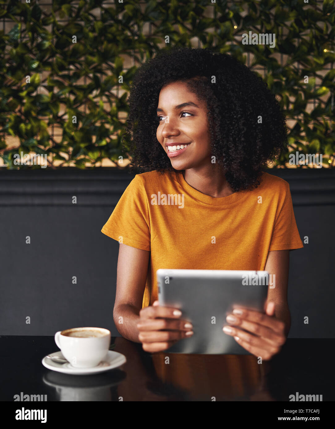 Young woman in cafe holding digital tablet looking away Banque D'Images