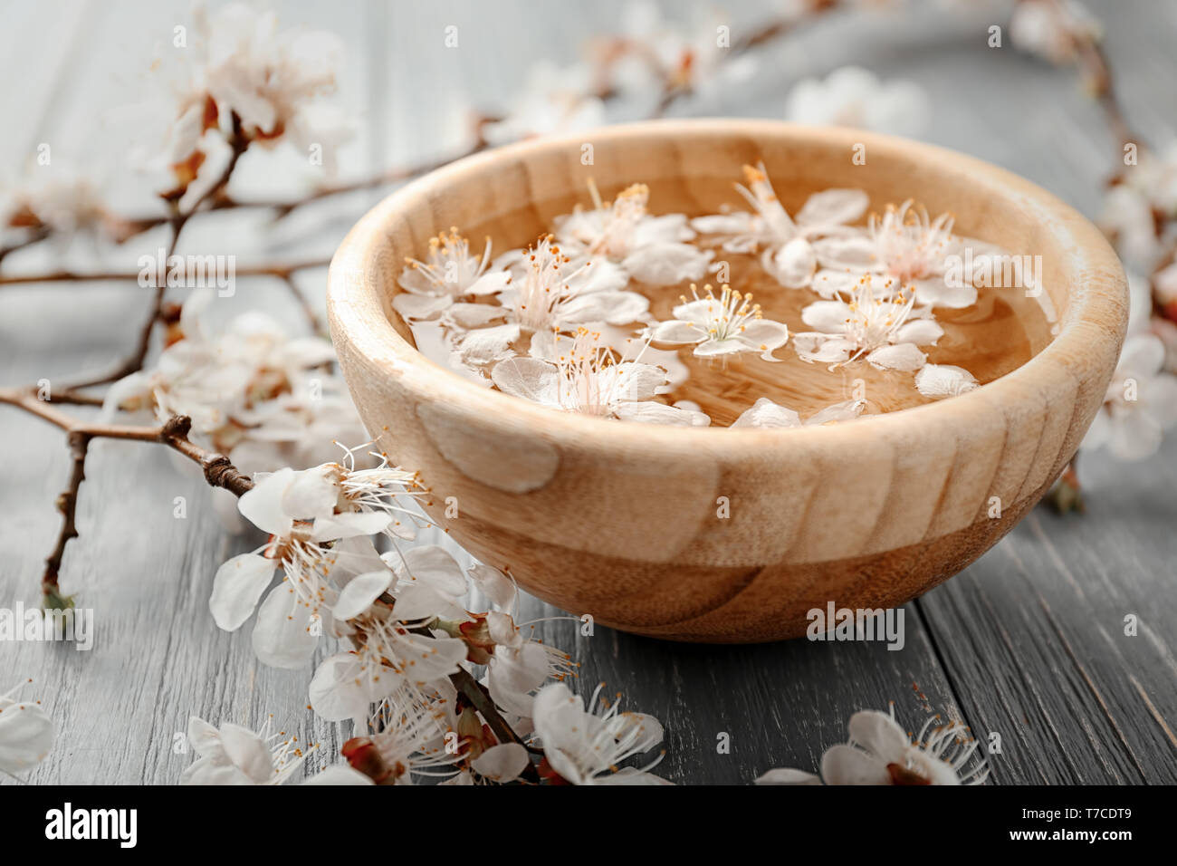 Bol avec de l'eau et de fleurs sur fond de bois Banque D'Images