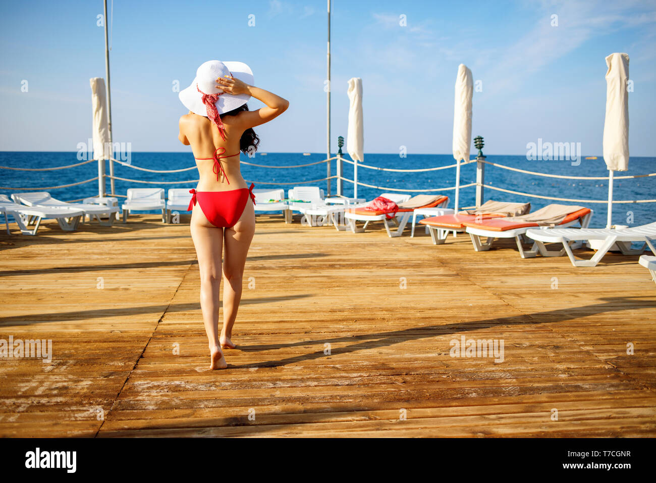 Jeune femme en maillot de bain sur la plage et jetée en bois. Banque D'Images