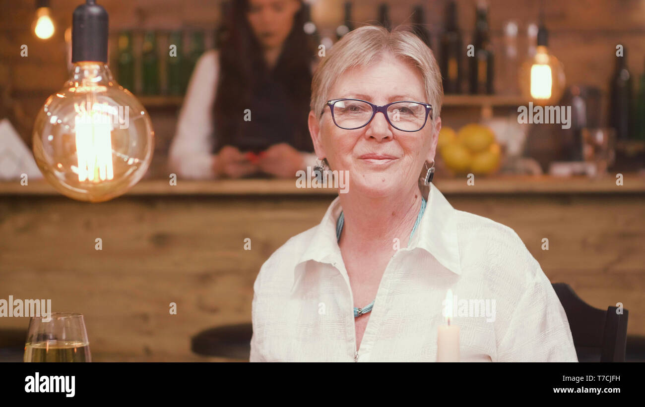 Portrait of senior woman in a restaurant regardant la caméra. Vieille Femme détendue. Femme dans la soixantaine. Banque D'Images
