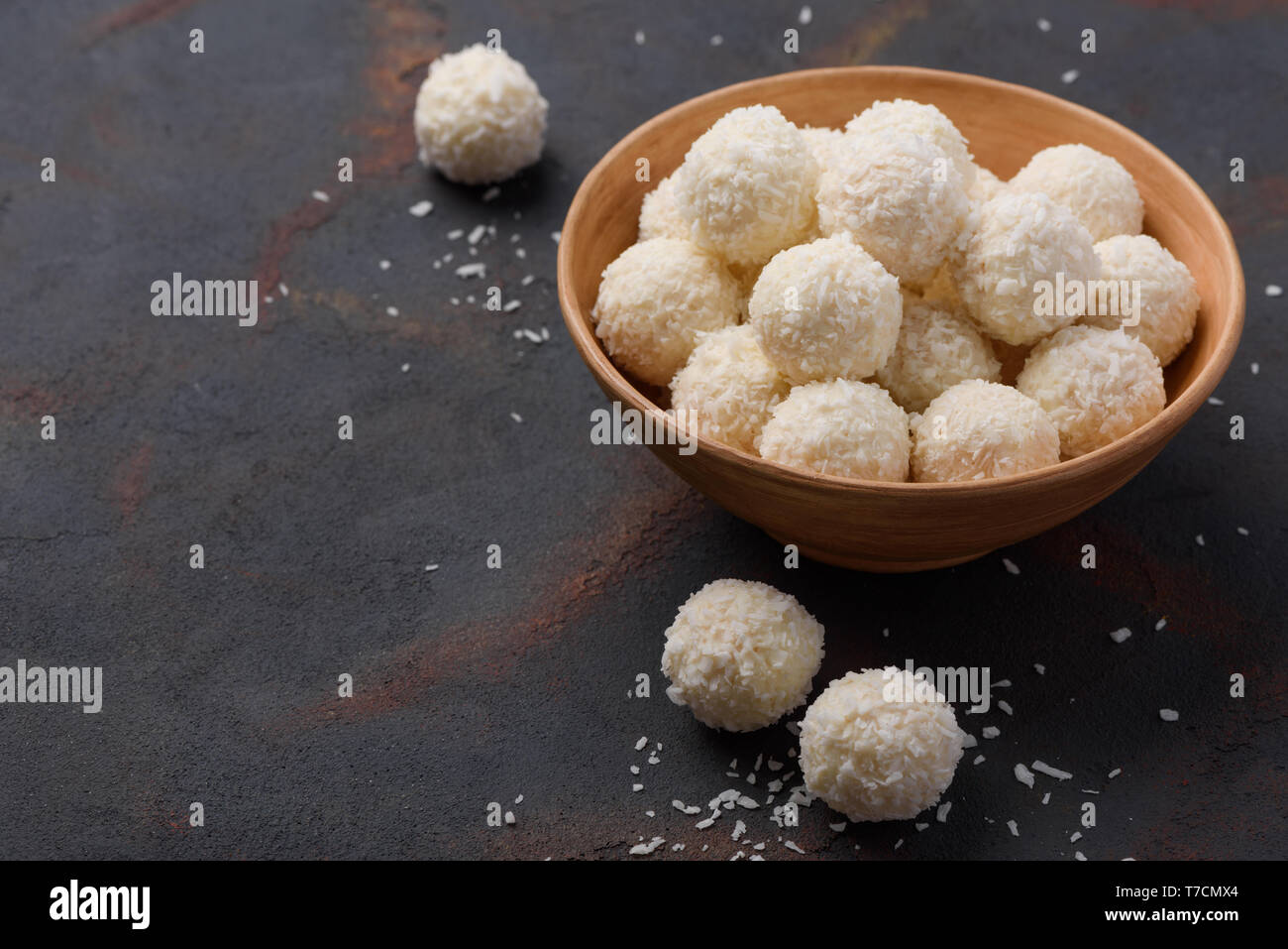 Flocons de noix de coco bonbons dans bol sur arrière-plan du tableau sombre Banque D'Images