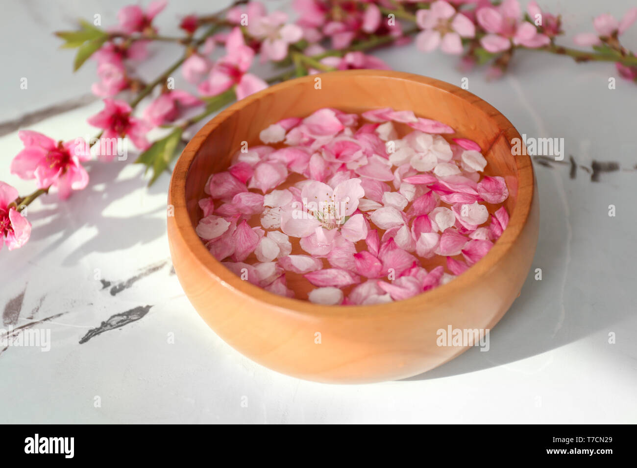 Bol en bois avec de l'eau et de fleurs sur la table Banque D'Images