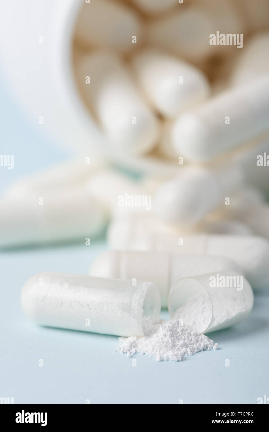 Comprimé déversés par bouteille ouverte avec fond blanc macro. Concept de l'épidémie aux opiacés. Banque D'Images