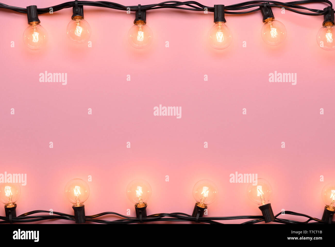 Chaîne de l'ampoule de la lumière. Edison garland rétro éclairage chaud rose sur fond pastel. Banque D'Images