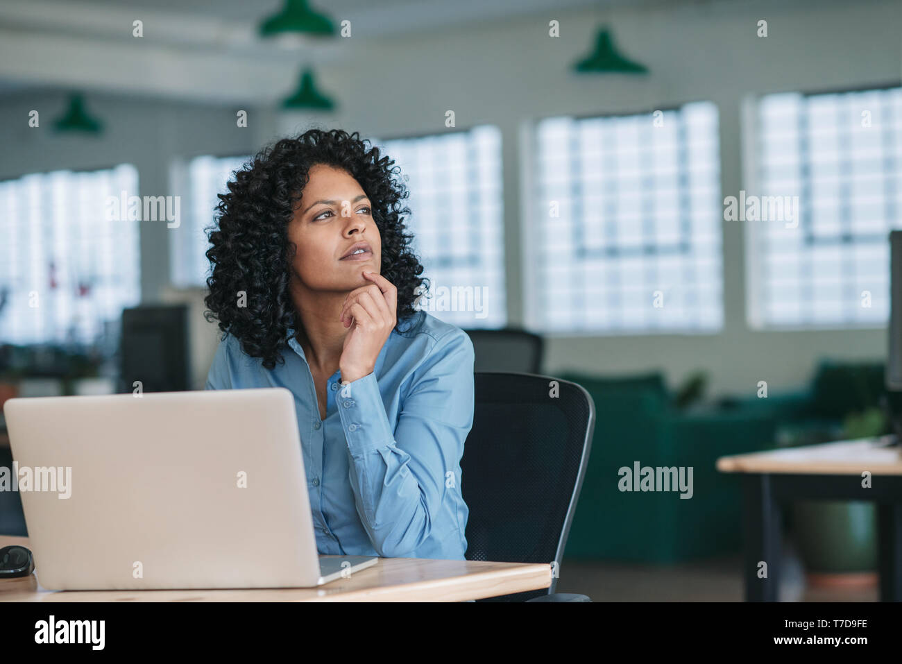 Young businesswoman thinking lors de l'utilisation d'un ordinateur portable au travail Banque D'Images