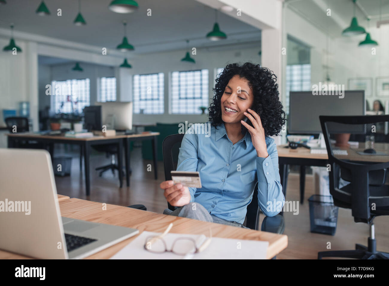 Smiling businesswoman en utilisant sa carte de crédit par téléphone Banque D'Images