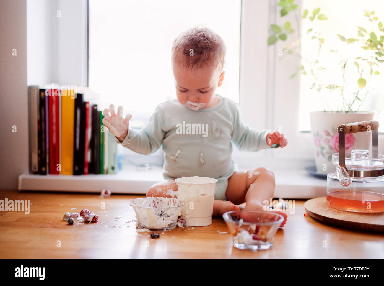 Un Petit Bebe Garcon Malpropre Assise Sur Comptoir De La Cuisine A La Maison Manger Des Fruits Et Des Yaourts Photo Stock Alamy